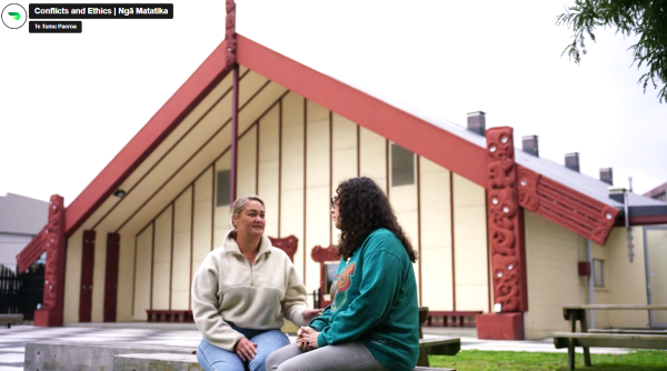 Two women talking outside a marae, still from video 